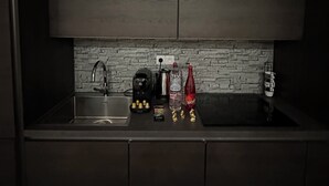 Une cuisine moderne dotée d’un plan de travail foncé, d’une cuisinière encastrée, d’un évier et d’un mur de fond en briques.