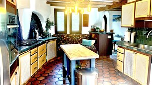 Une cuisine de taille réduite dotée d’un îlot central, de meubles en bois, d’une cuisinière et d’un luminaire suspendu.