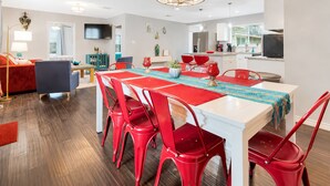 Un espacio habitable moderno con comedor, cocina y televisor montado en la pared.