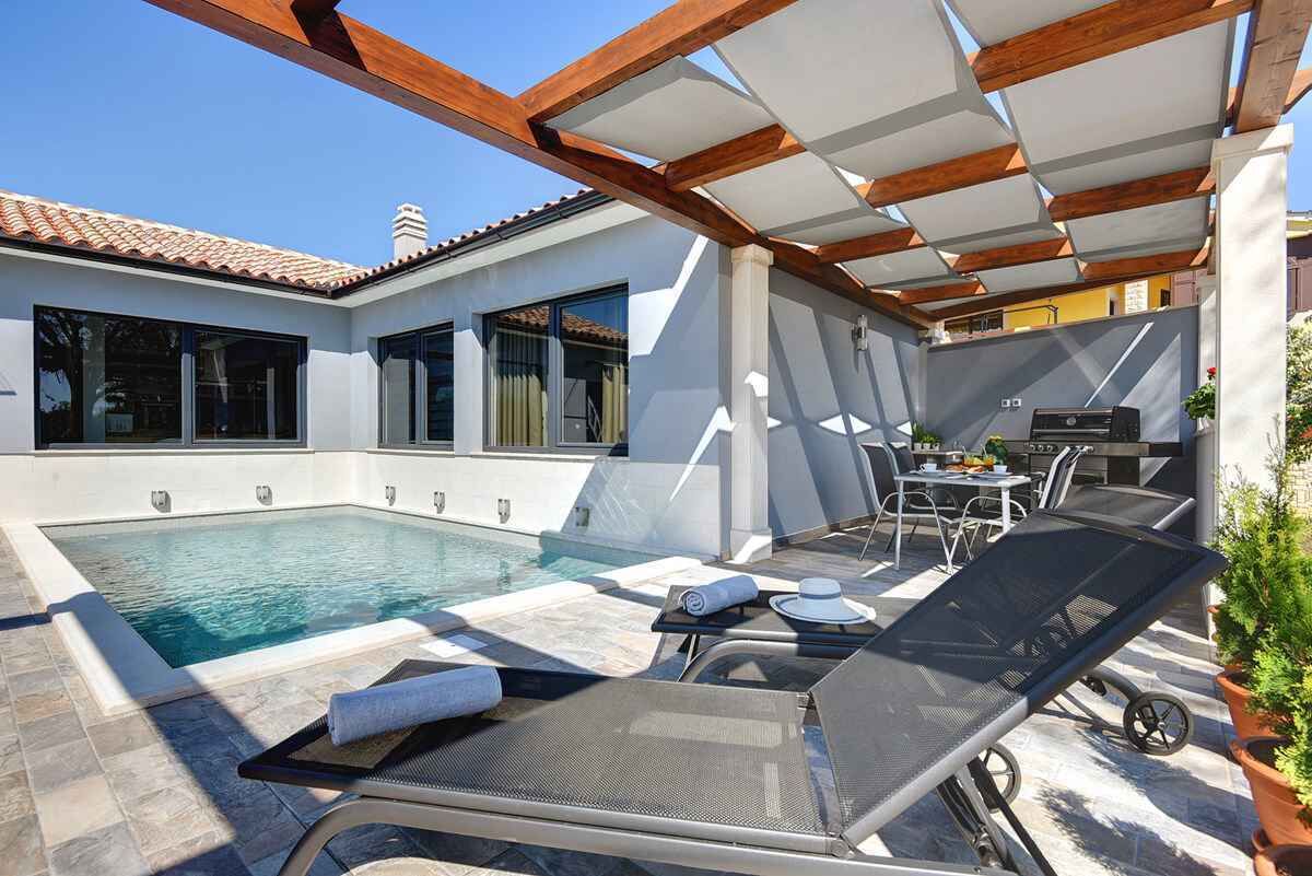 A modern outdoor pool area with lounge chairs and a dining table.
