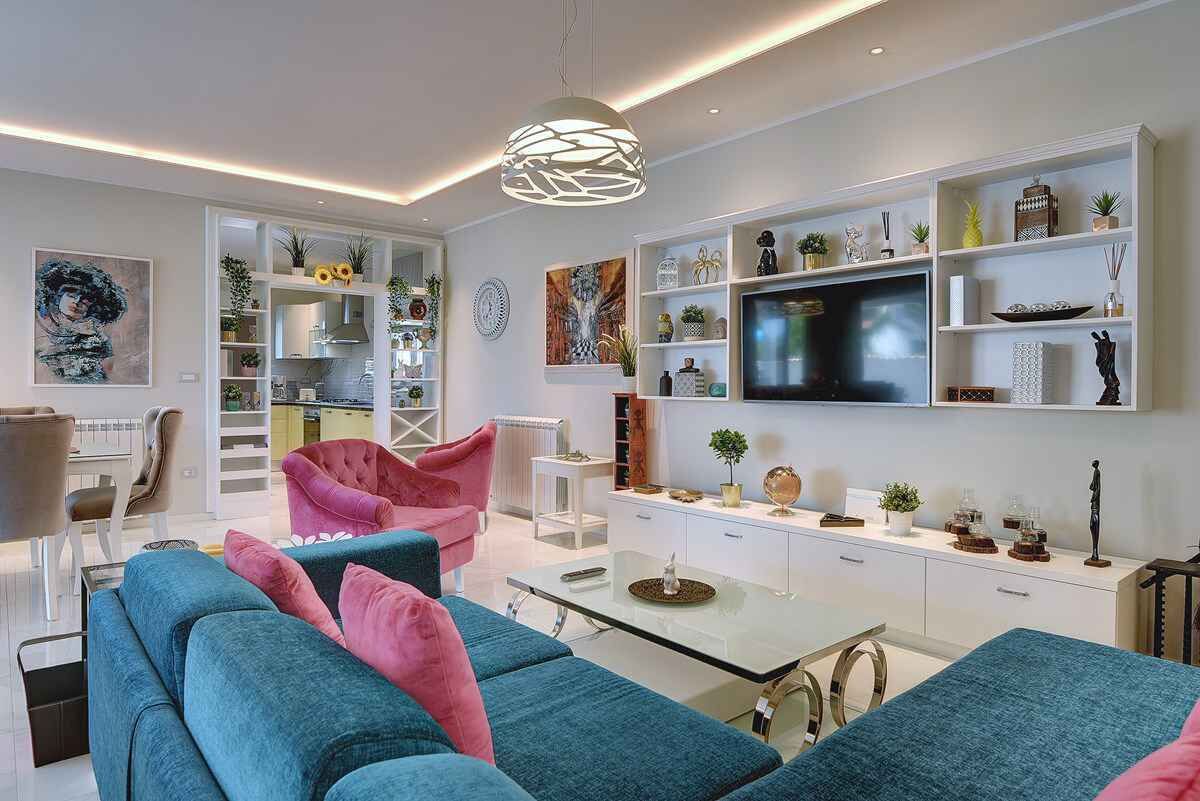 A modern living room with a sofa, chairs, a coffee table, and a TV.