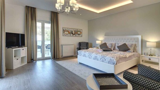 A modern bedroom with a large bed, a television, and a balcony. - Villa with heated pool (Premantura)