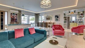 A modern living room with a pool table, a sofa, a coffee table, and a dining area with chairs. - Villa with heated pool (Premantura)