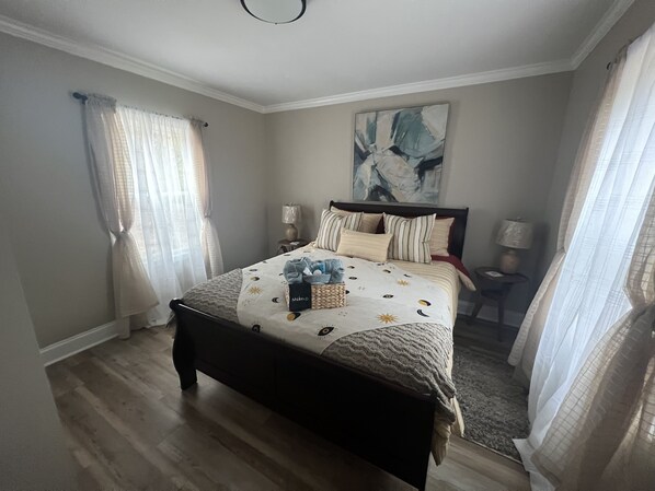A bedroom with a bed, two bedside tables, a nightstand, and a large abstract painting on the wall.
