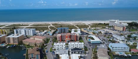 Vista aérea de una zona hotelera costera con varios edificios, un puerto deportivo y una playa al fondo.