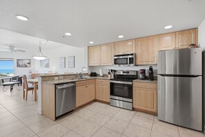 A modern kitchen with stainless steel appliances, wooden cabinets, and a granite countertop.