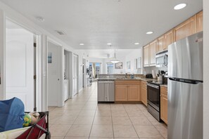 A modern kitchen with stainless steel appliances, wooden cabinets, and a tiled floor. - Starfish Sands: Gulf View, Beach Access, & Pool (Treasure Island)