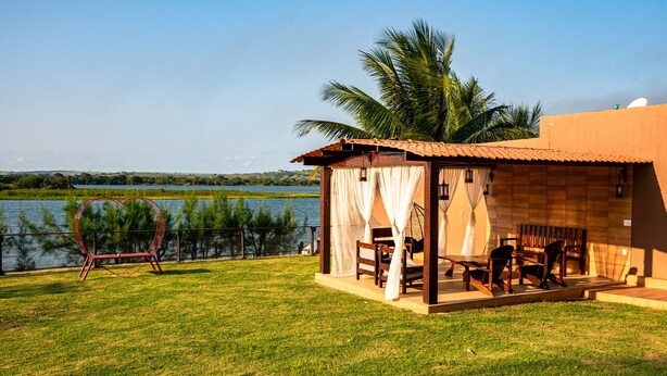 A small wooden structure with a covered patio, a chair, and a table. - Pousada Vida de Rio (Santana do Sao Francisco)