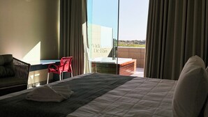 A hotel room with a large bed, a desk, a chair, and a view of the outdoors. - Pousada Vida de Rio (Santana do Sao Francisco)