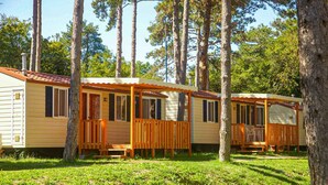 Une rangée de maisons mobiles dotées de terrasses en bois, séparées par une zone herbeuse.