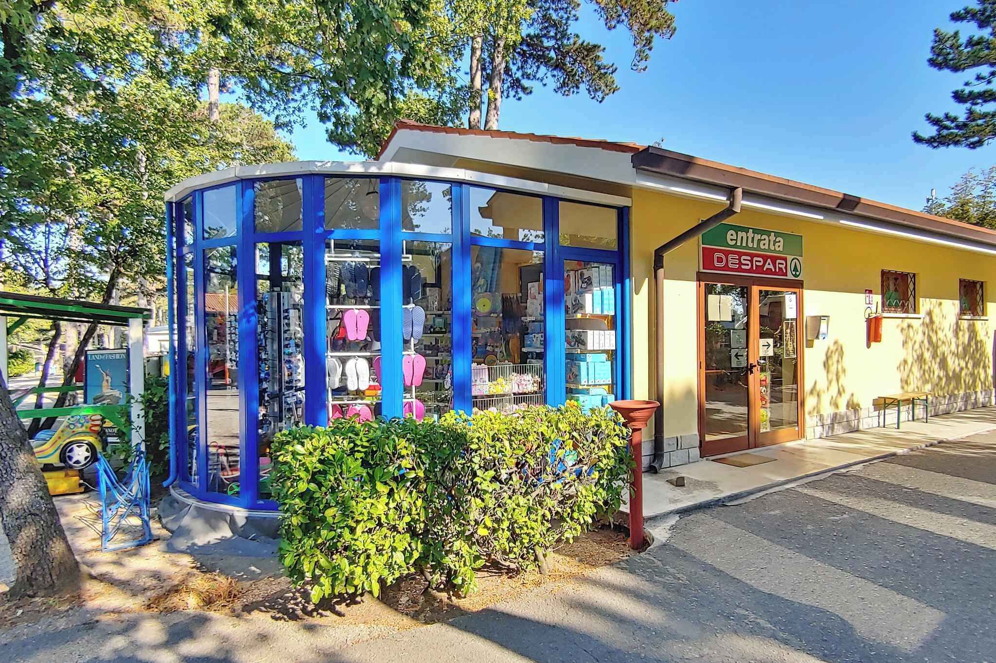 Une devanture de magasin avec une façade en verre bleu, une enseigne indiquant « ENTRATA DESPAR » et une petite enseigne verte sur laquelle on peut apercevoir le mot « INDIVINDA ».