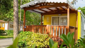Un bâtiment jaune doté d’une terrasse en bois et d’un porche abrité.
