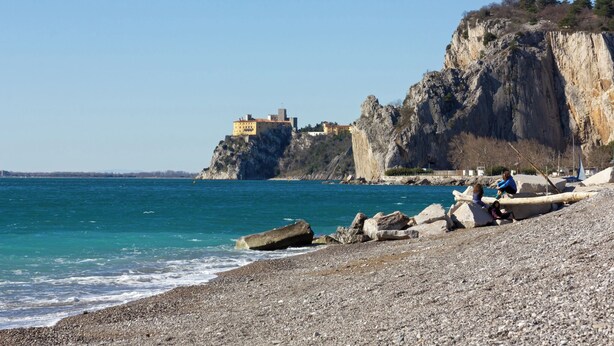 A rocky beach with a large cliff and a building on top. - Holiday apartment with a/c (Duino-Aurisina)