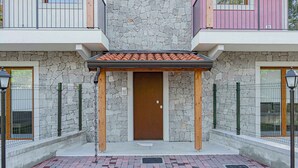 A building entrance with a stone facade, a wooden door, and a tiled roof. - Holiday apartment with a/c (Duino-Aurisina)