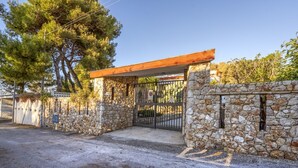 A stone-walled building with a metal gate, a paved entrance, and a clear sky.