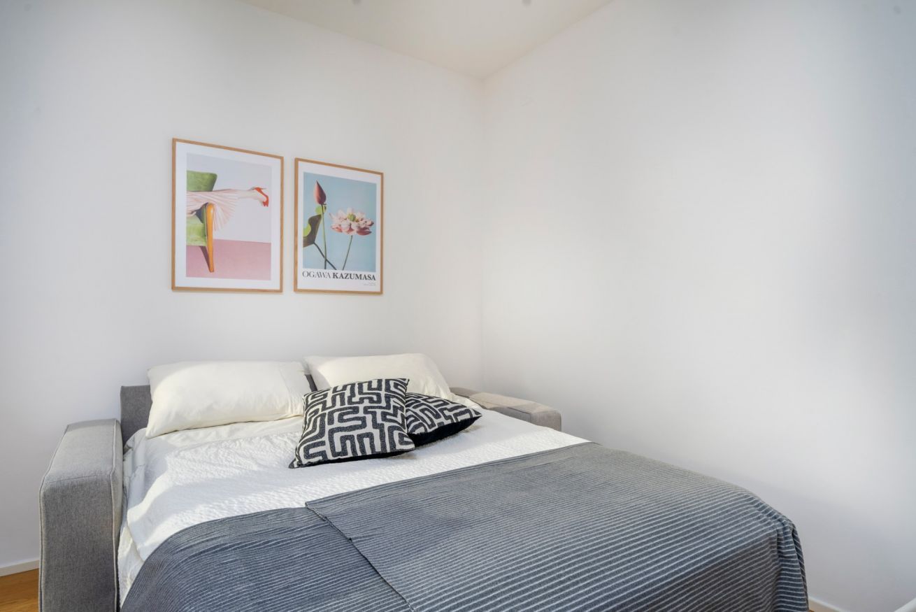Ein Schlafzimmer mit einem Bett, Kissen und zwei gerahmten Kunstwerken an der Wand.