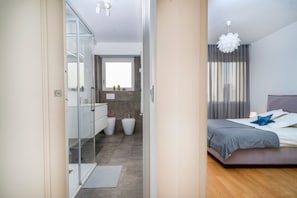 A modern bedroom with a bed, a bedside table, and a window with curtains.