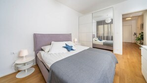 A modern bedroom with a bed, bedside tables, a mirror, and a wardrobe. - GuestHost - Cozy & Bright Apartment - w/ Balcony (udine)