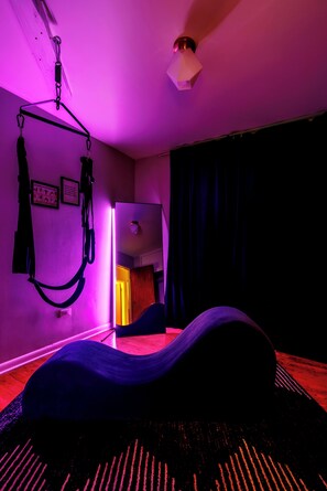 Ein Zimmer mit an der Decke befestigtem Trainingsgerät, einem Bett mit blauer Matratze und einem gemusterten Teppich.