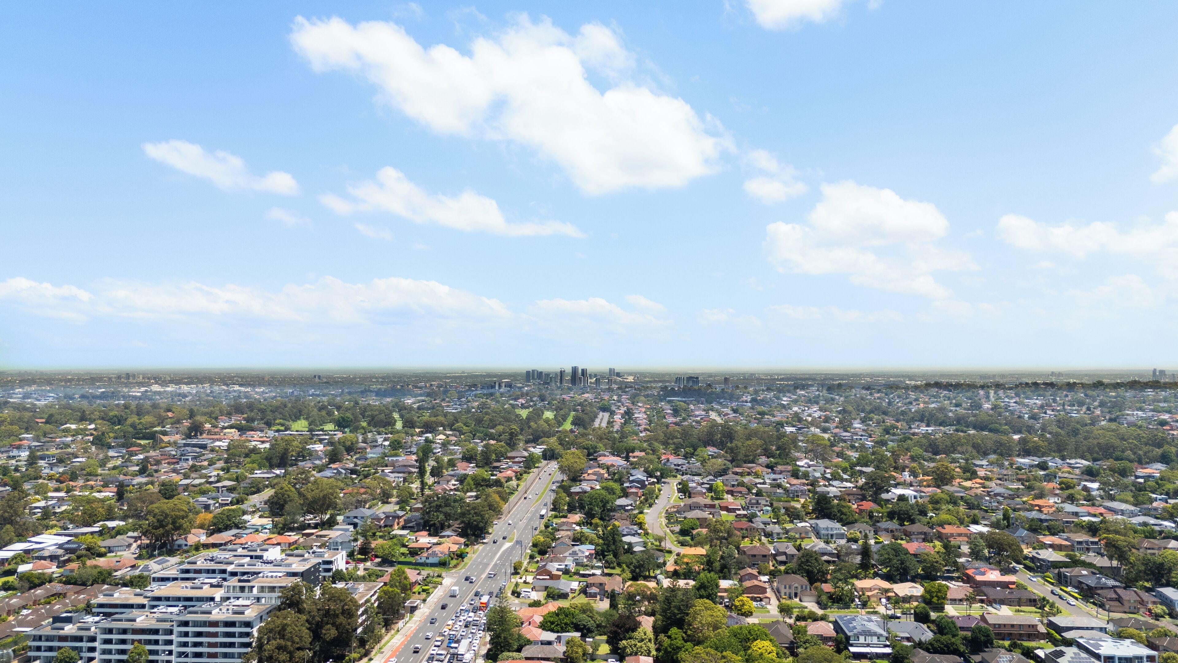 A wide-angle view of a cityscape with residential areas, roads, and distant buildings.