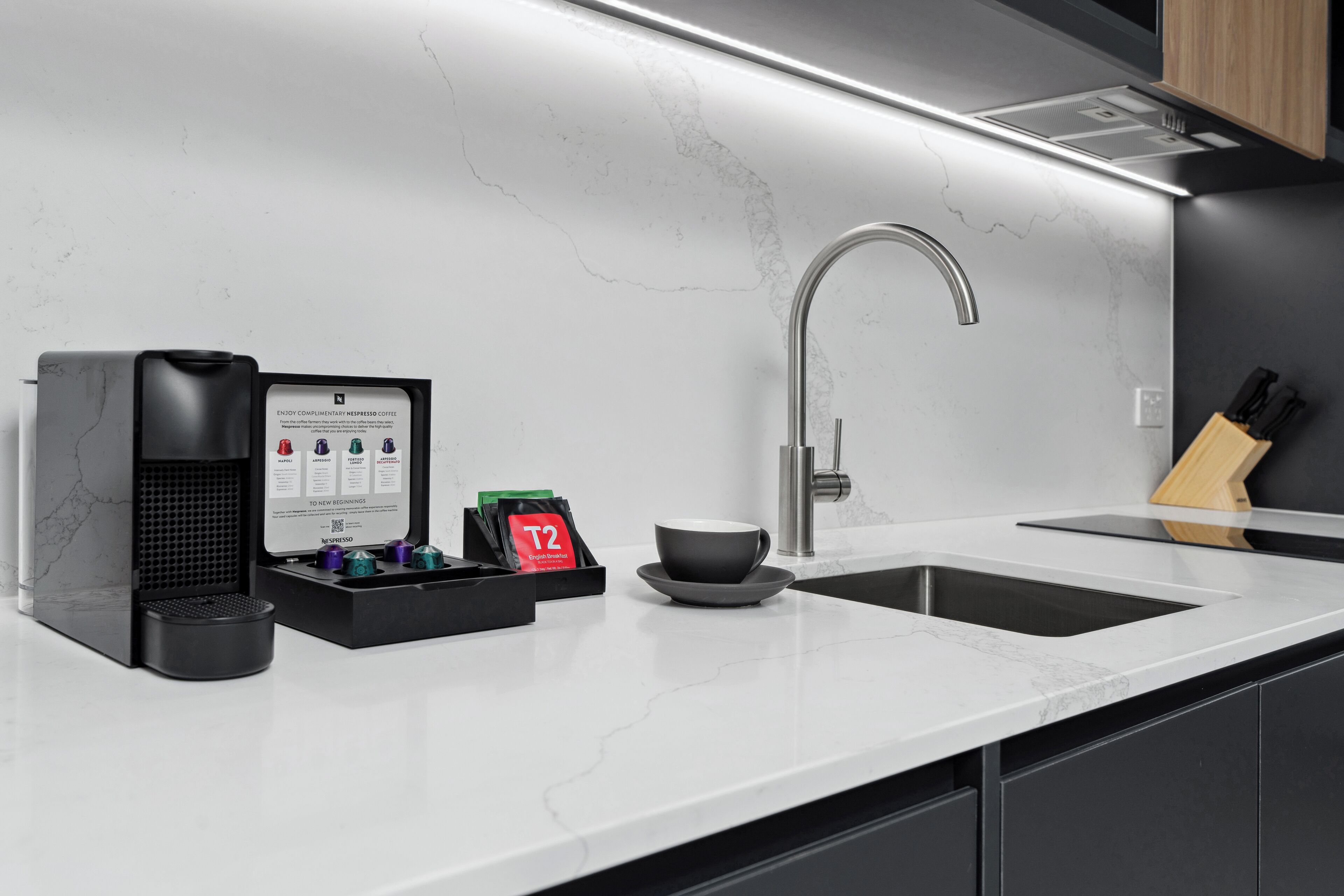 A modern kitchen with a sleek espresso machine, a sink, and a countertop.