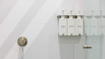 A bathroom with a modern design, featuring a toilet, a sink with a soap dispenser, and a mirror.