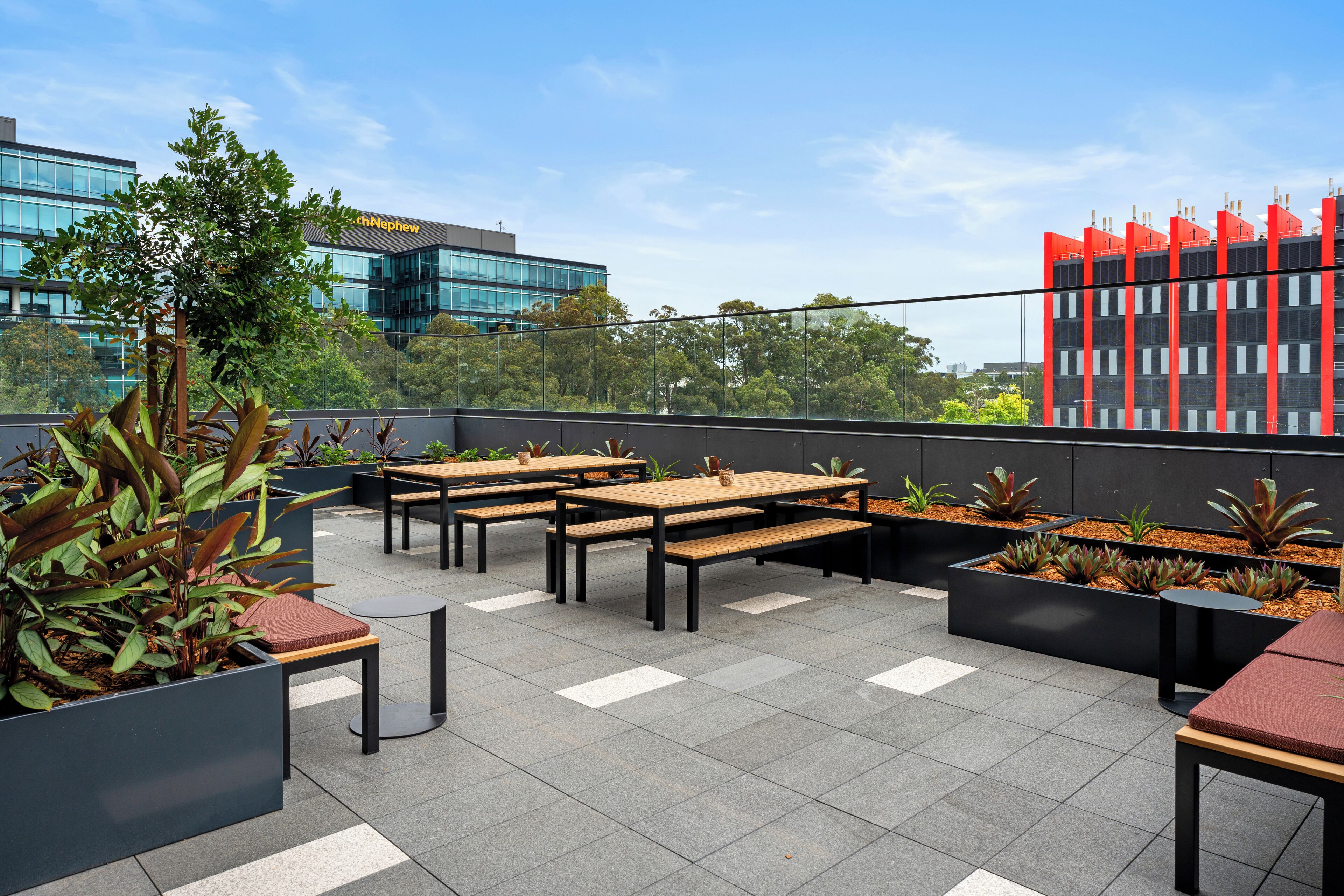 Terraza al aire libre con varias mesas y bancos de madera, rodeada de macetas con diversas plantas.