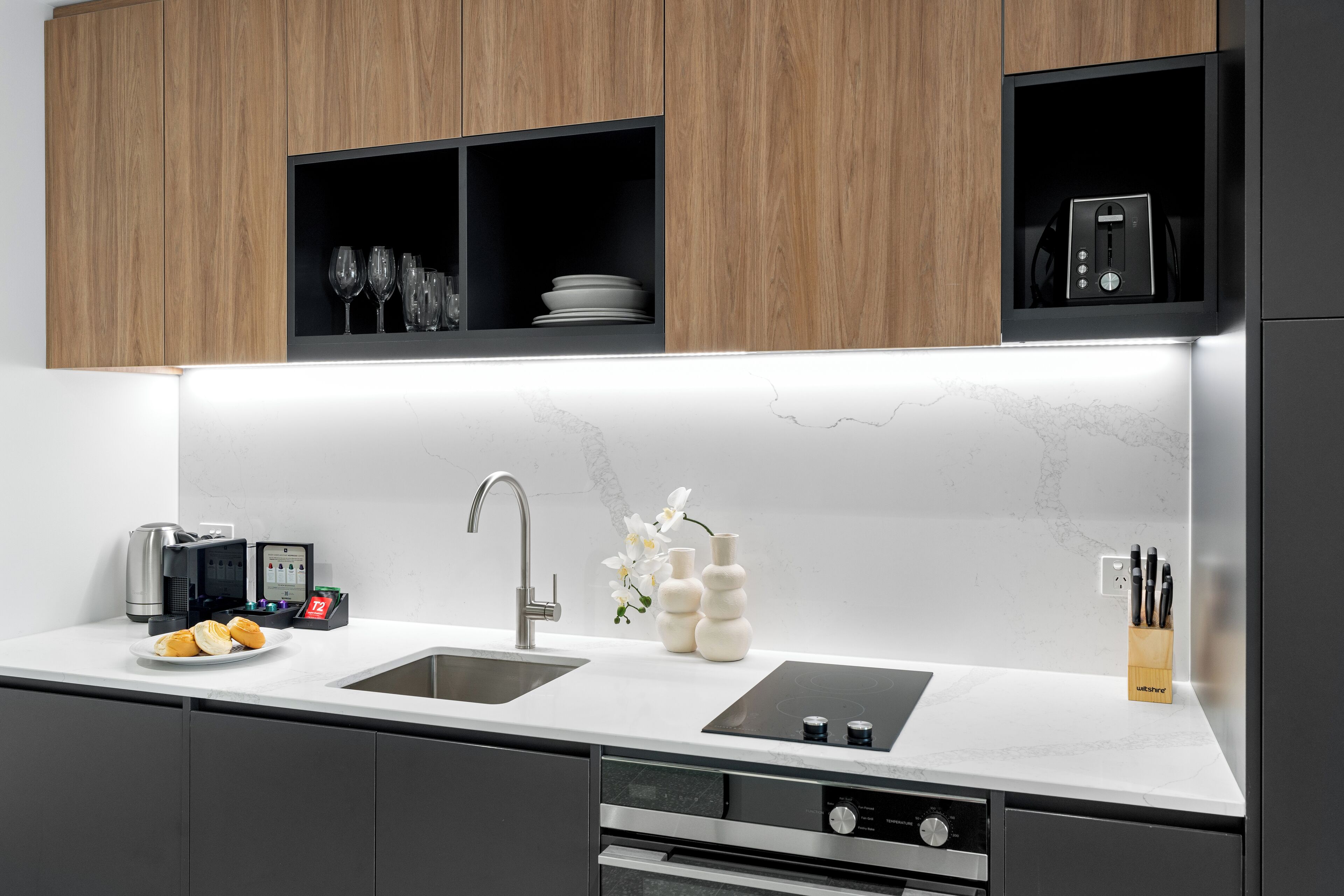 A modern kitchen with a double sink, built-in appliances, and wooden cabinets.