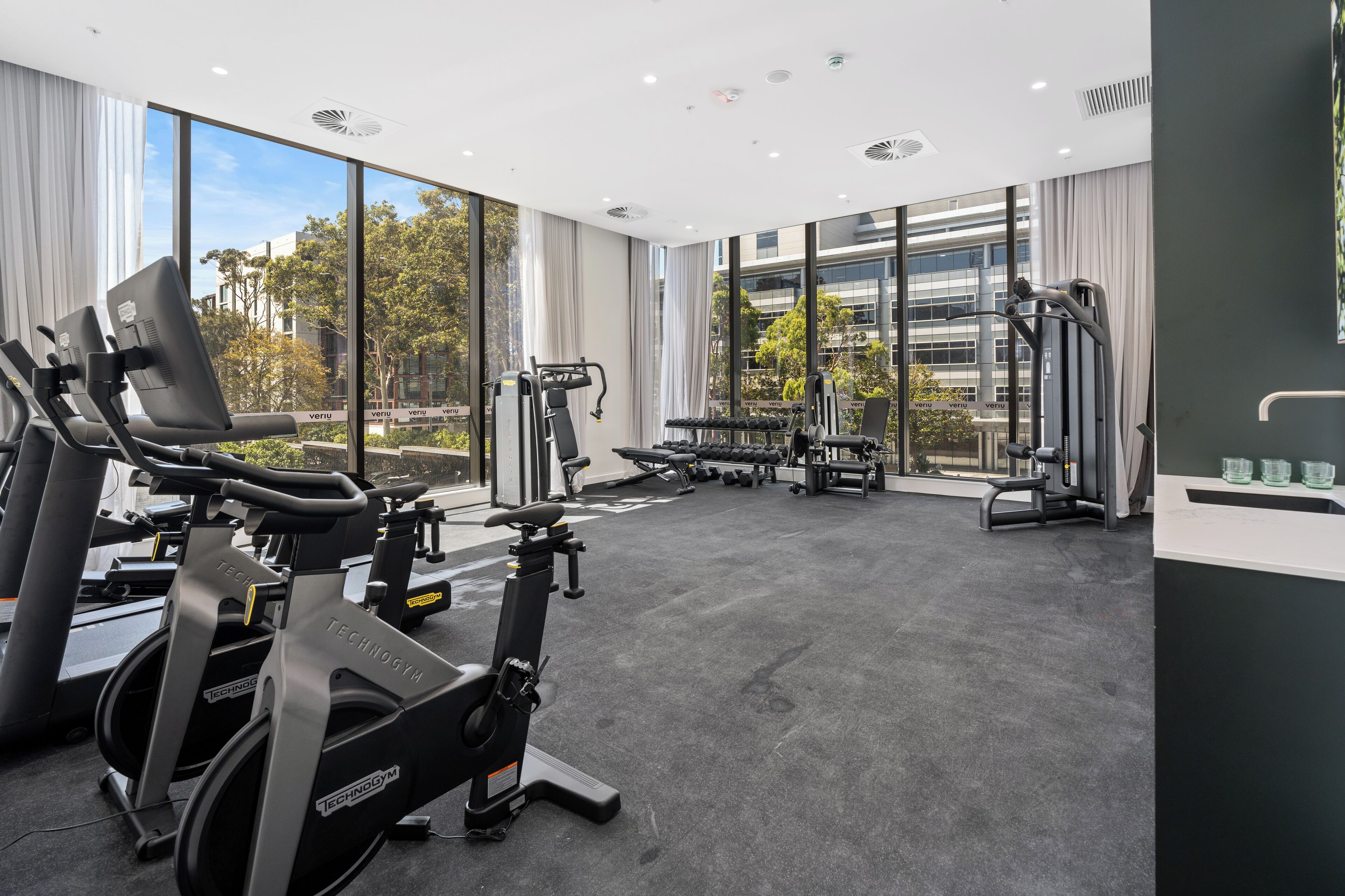Un gimnasio con máquinas de cardio, bancos de pesas y pesas libres.