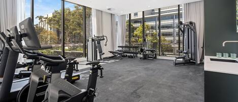 Un gimnasio con máquinas de cardio, bancos de pesas y pesas libres.