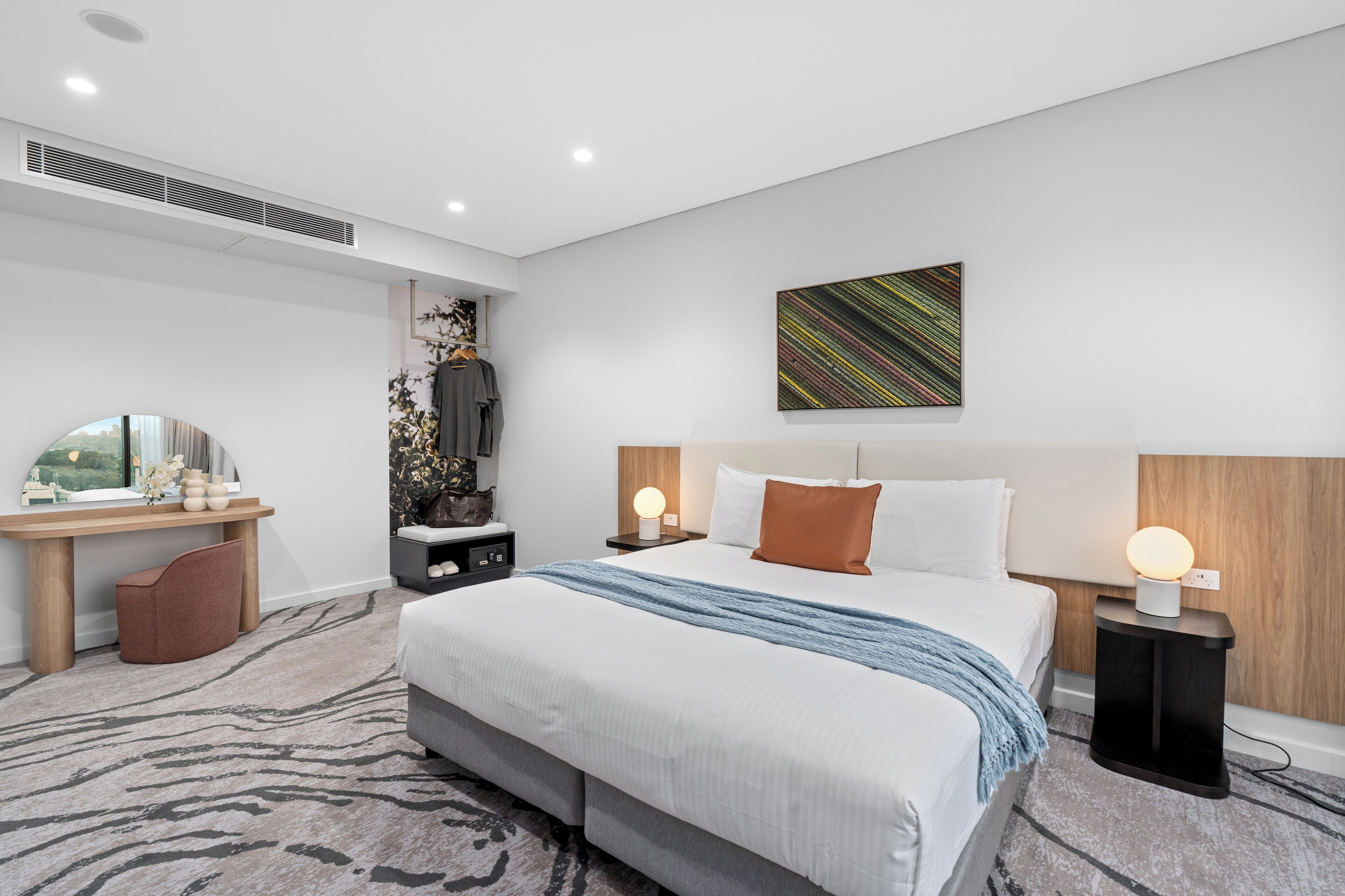 Een moderne hotelkamer met een groot bed, een bureau en een nachtkastje.