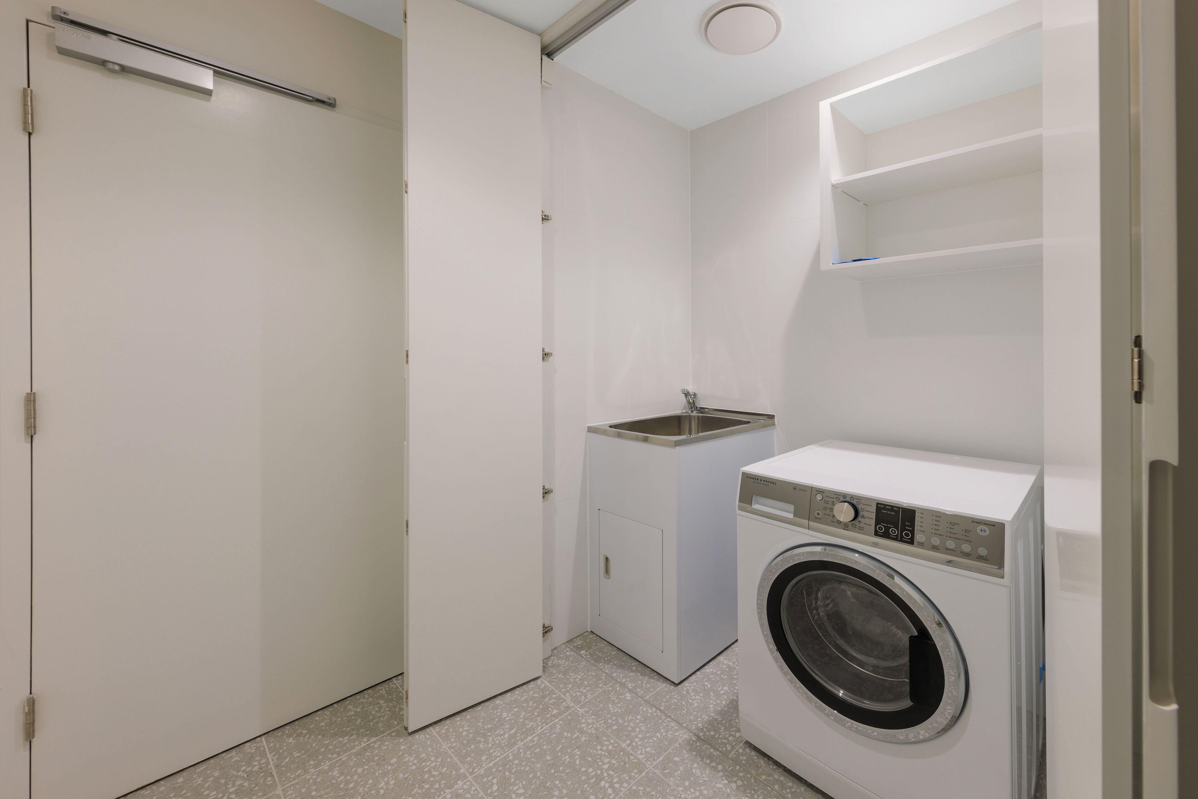 A compact laundry room with a washing machine, a sink, and a cabinet.