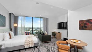 Una habitación de hotel moderna con una cama grande, un escritorio, un sofá y un comedor.