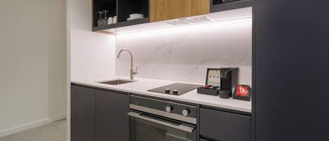 Una cocina moderna con horno de acero inoxidable, un lavamanos integrado y armarios de madera arriba.