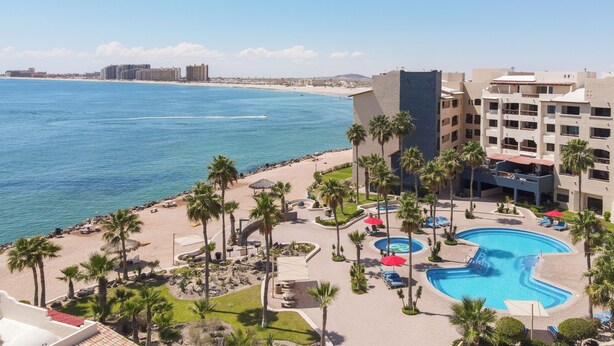Ein Resort mit Pool, Palmen und Blick auf den Strand.