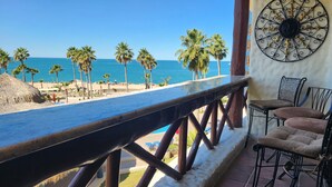 Ein Balkon mit Blick auf den Strand, Palmen und einer Zierwand.