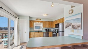 Una cocina con armarios de madera, un refrigerador de acero inoxidable, un microondas y una isla grande con taburetes.