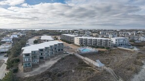 A coastal residential area with modern multi-story buildings, a swimming pool, and a beach access walkway. - 2971 - Seabbatical - Duck Oceanfront Condo | Direct Beach Access (Duck)