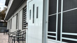 A building with a sliding glass door, a patio with stone tiles, and outdoor seating.