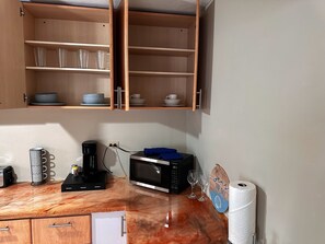A kitchen with wooden cabinets, a microwave, a coffee maker, and a roll of paper towels.