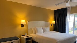Una camera d'albergo con un letto, lampade sui comodini, un comodino, una scrivania e una ventola a soffitto.