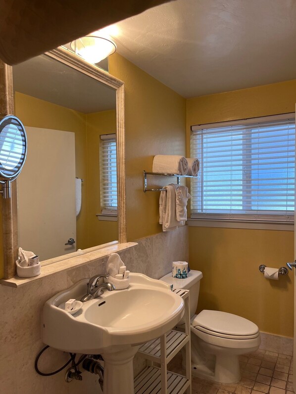 A bathroom with a sink, toilet, and a window with blinds.