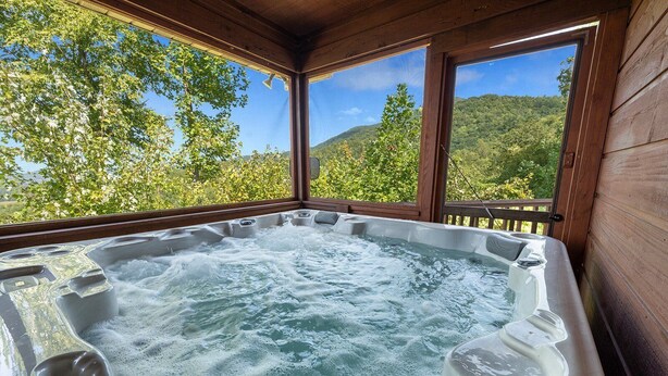 A hot tub with a wooden deck and large windows overlooking a forested hillside. - Little Little: Pet Friendly, Free Attraction Tickets, Hot Tub, Views & Hiking Trails (Sevierville)
