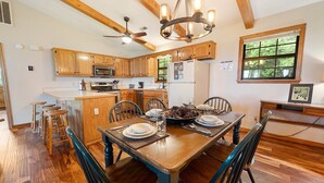 A spacious kitchen with wooden cabinets, a central island, and a dining area with a wooden table and chairs. - Little Little: Pet Friendly, Free Attraction Tickets, Hot Tub, Views & Hiking Trails (Sevierville)