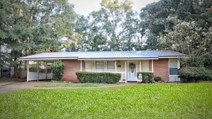 A single-story house with a covered porch, a front door with a wreath, and a well-maintained lawn.