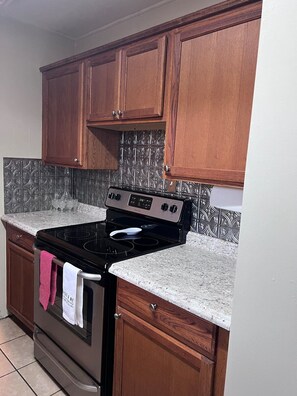 Una cocina con armarios de madera, estufa negra y salpicadero de azulejos.