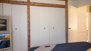 A bedroom with a bed, a wardrobe, and a door leading to another room.