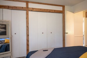 Een slaapkamer met een bed, een kledingkast en een deur naar een andere kamer.