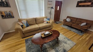 A living room with two sofas, a coffee table, and a rug. - Cozy 3BR Lawrenceville Haven close to everything (Lawrenceville)