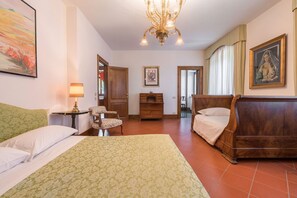 Relax in a traditional room with a large bed, wooden furniture, and a classic chandelier.